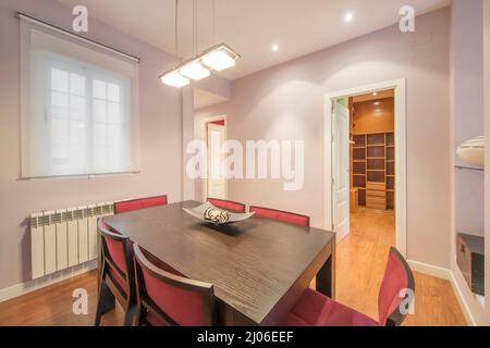 room with dark wood dining table and red velvet upholstered chairs with purple painted walls Stock Photo