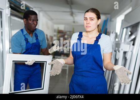Two masters are conflicting in time working with window frame in the window workshop. Stock Photo