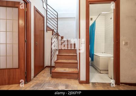Distributor of a duplex house with a bathroom, entrance to a living room with a glass door and stairs to the second floor Stock Photo