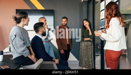 Young businesspeople discussing some reports in a boardroom. Group of multicultural businesspeople having a meeting in a modern office. Young entrepre Stock Photo