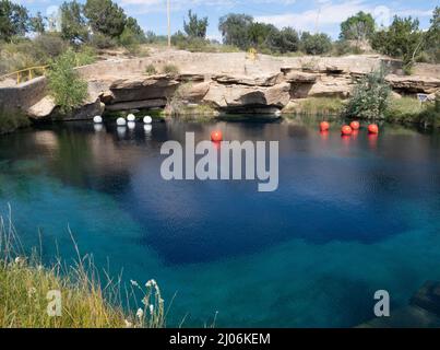 Park in Santa Rosa, New Mexico, with the Blue Hole popular with swimmers and divers. White and red dive buoys are on the surface of the water. Stock Photo