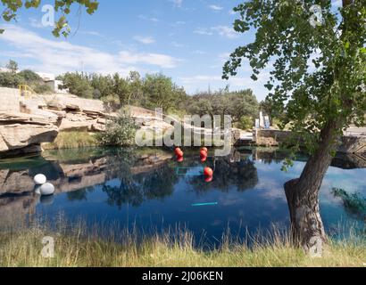 Park in Santa Rosa, New Mexico, with the Blue Hole popular with swimmers and divers. White and red dive buoys are on the surface of the water. Stock Photo