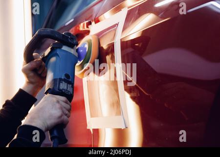 Master mechanic removal of dents defects auto repairman grinding automobile car body. Stock Photo