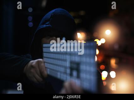 Armed and ready to destroy your data. Shot of an unrecognisable hacker holding a keyboard in the dark. Stock Photo