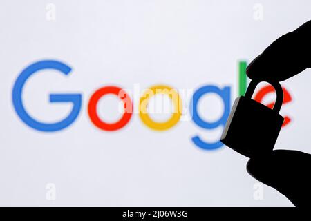 Fingers hold a closed security lock on the background of the Google technology company logo. The concept of data security in Google. Stock Photo