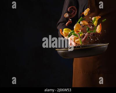 Assorted seafood - red fish, shrimps, octopus with vegetables. Close-up, black background. There is an empty space to insert. Cooking seafood dishes. Stock Photo