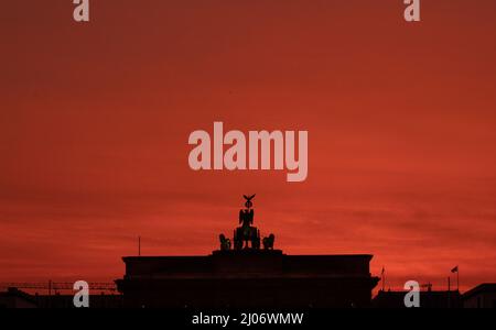 Berlin, Germany. 17th Mar, 2022. Colorful is the sky above the Brandenburg Gate for a moment at sunrise. Credit: Paul Zinken/dpa/Alamy Live News Stock Photo