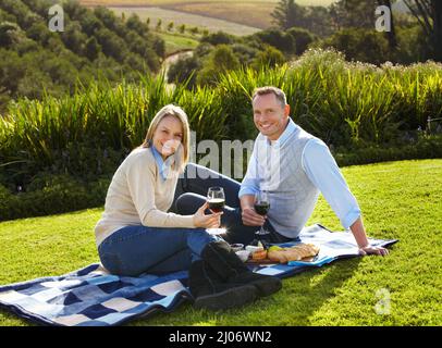 Out on the perfect picnic. Portrait of a loving mature couple enjoying a picnic on the grass. Stock Photo