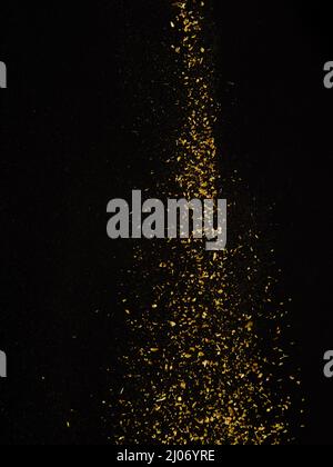 Golden flow of exotic spices in frozen flight on black background. Cooking, spices, seasonings, spicy dishes, sauces. Recipes for restaurant and home Stock Photo