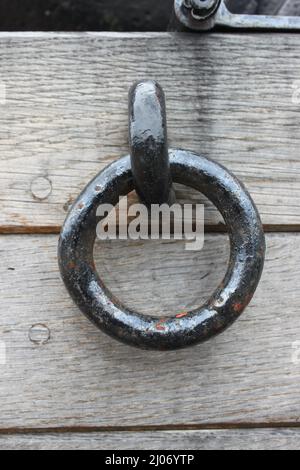 one black iron ring is attached to a washed out wooden wall Stock Photo