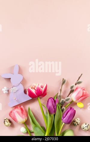 Easter composition with colorful Easter eggs and spring flowers tulips over pink background. Spring and Easter holiday concept. Top view flat lay. Stock Photo