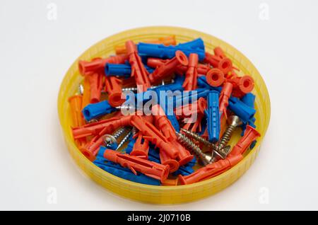Screws and dowels in round plastic box on white background Stock Photo