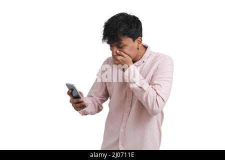 Young peruvian man surprised using the smartphone, isolated. Stock Photo