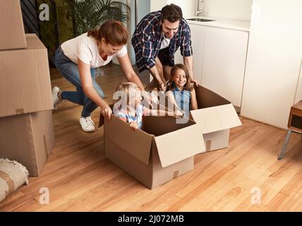 Playing around while unpacking. Shot of a young family on their moving day. Stock Photo