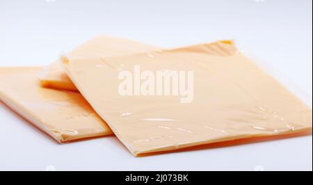 sliced pieces of cheese in plastic on white background Stock Photo