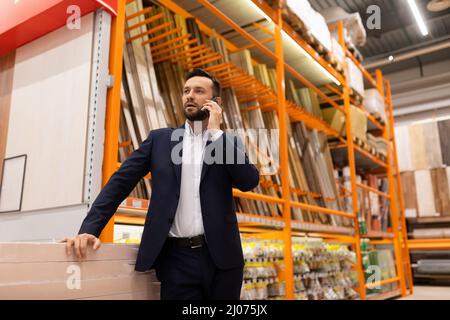 a male customer at a hardware store in the lumber department speaks on the phone Stock Photo