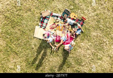 Aerial drone view of happy families having fun with kids at picnic barbecue party - Multiracial happiness and love concept with mixed race people play Stock Photo