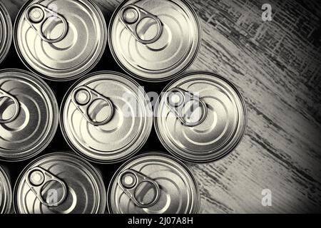 Close up, top down view of a group of tin cans with easy open on a wooden surface. Monochromatic image Stock Photo
