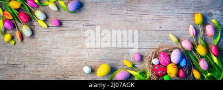 Easter Eggs - Painted Decoration In Nest With Tulips On Natural Wooden Plank Stock Photo