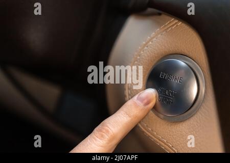Woman pressing engine start and stop button in luxury sport car close-up view photo Stock Photo