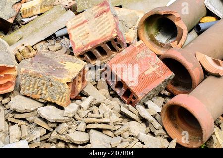 Close up of a pile of construction waste after demolishing an old building. Broken bricks, cement pieces and stoneware water-supply pipes. Stock Photo