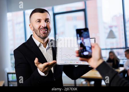 A successful male businessman is recording a webinar course on working with trading in the stock market. Online lessons for business. Development of a Stock Photo