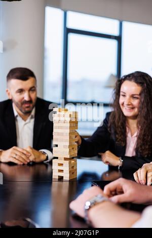 Friends build a tower from wooden blocks on the table, teamwork concept. Board game jenga. selective focus Stock Photo