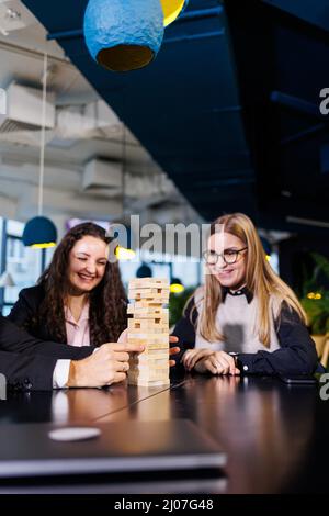 Friends build a tower from wooden blocks on the table, teamwork concept. Board game jenga. selective focus Stock Photo