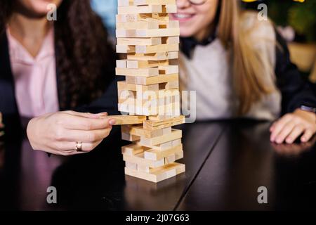 Friends build a tower from wooden blocks on the table, teamwork concept. Board game jenga. selective focus Stock Photo