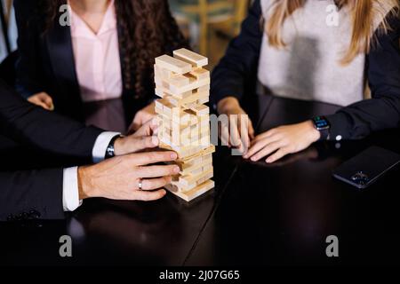 Friends build a tower from wooden blocks on the table, teamwork concept. Board game jenga. selective focus Stock Photo