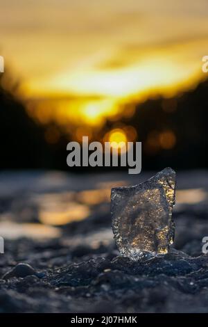 Transparent piece of ice on the blurred background of the sunset Stock Photo
