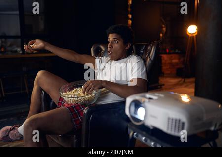 Surprised indignant man watching film on projector Stock Photo