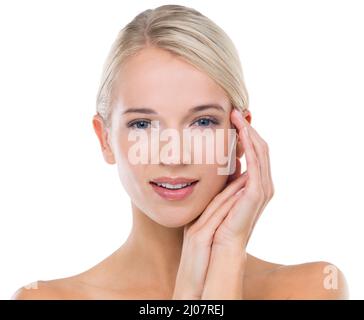 Nothing quite like the feeling of smooth, soft skin. Studio shot of a beautiful blonde touching her face against a white background. Stock Photo