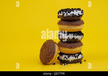 chocolate donuts on a yellow background. donuts are stacked on top of each other ,Woman holding tower of doughnuts stacking on top of each other Stock Photo
