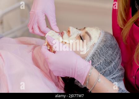 Face peeling mask, spa beauty treatment, skincare. Woman getting facial care by beautician at spa salon, side view, close-up . beauty salon ... Stock Photo