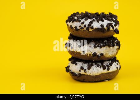 three chocolate donuts on a yellow background ,Three chocolate donuts with sprinkles, on yellow background Stock Photo