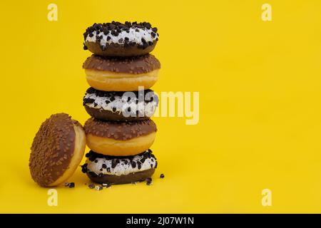 chocolate donuts on a yellow background. donuts are stacked on top of each other ,Woman holding tower of doughnuts stacking on top of each other Stock Photo