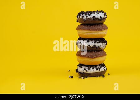chocolate donuts on a yellow background. donuts are stacked on top of each other ,Woman holding tower of doughnuts stacking on top of each other Stock Photo
