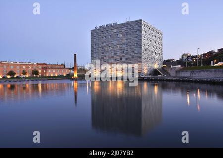 Modern Hotel Melia Ria and Congress Center (former factory building) reflecting in the Canal do Cojo at dusk, Aveiro Portugal.