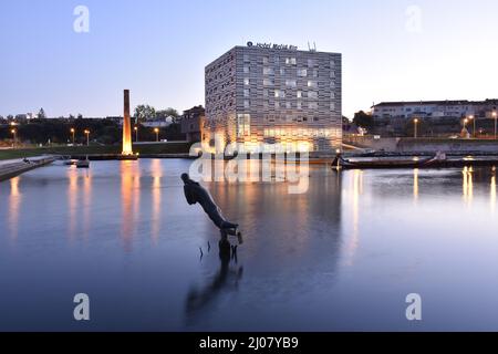 Hotel Melia Ria, modern building exterior at dusk by the Canal do Cojo in Aveiro Portugal.