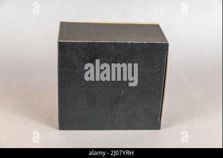 Rectangular black box on a gray background. Closed cardboard package with correct geometric shape. Stock Photo