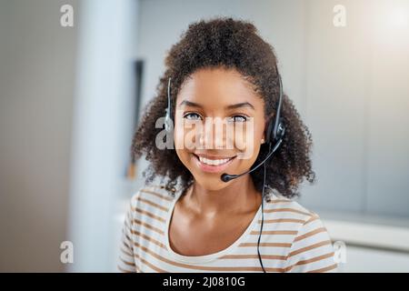 There are various ways you can get in touch. Portrait of a young woman wearing a headset while working on a computer at home. Stock Photo