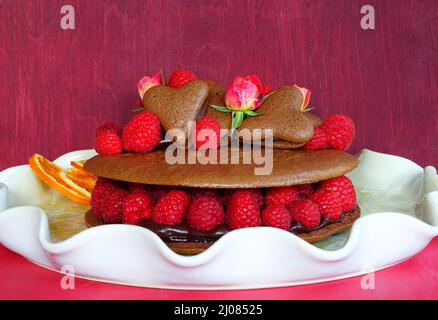 A giant chocolate macaron cake with fresh raspberries and rose flowers Stock Photo