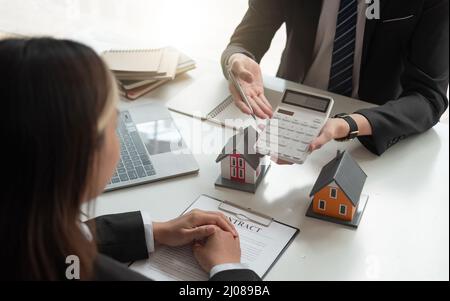 Real estate agent talked about the terms of the home purchase agreement and asked the customer to sign the documents to make the contract legally Stock Photo