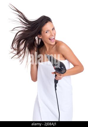 Blowing in the wind... of the hair dryer. An attractive woman expressing enjoyment while drying her hair. Stock Photo