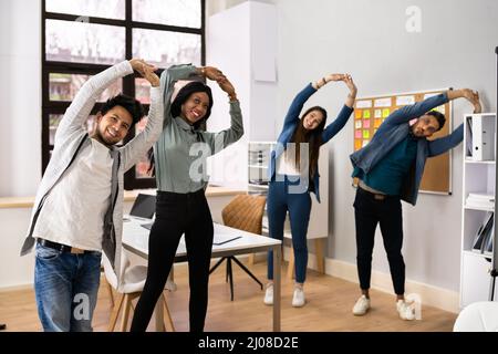 Group Of Happy Young Businesspeople Doing Stretching Exercise In Office Stock Photo