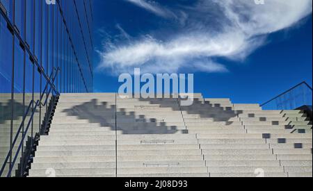 Looking up on empty concrete steps and clear blue sky with fluffy white clouds Stock Photo