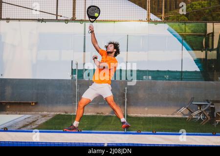 Padel match in a blue grass padel court - Handsome boy player playing a match Stock Photo