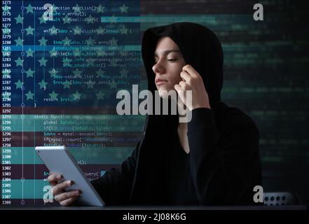 American hacker using tablet computer on dark background Stock Photo