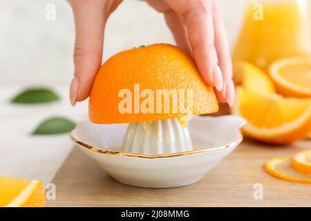Woman squeezing fresh orange on light background Stock Photo